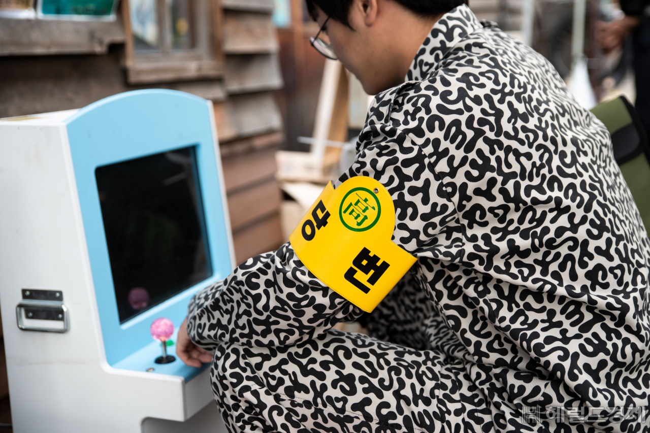 청계천 추억의 판잣집 체험마당에서 한 시민이 교련복을 입고 전자오락기를 하며 1960년대 풍경을 재현해보고 있다. [ 서울시설공단 제공]