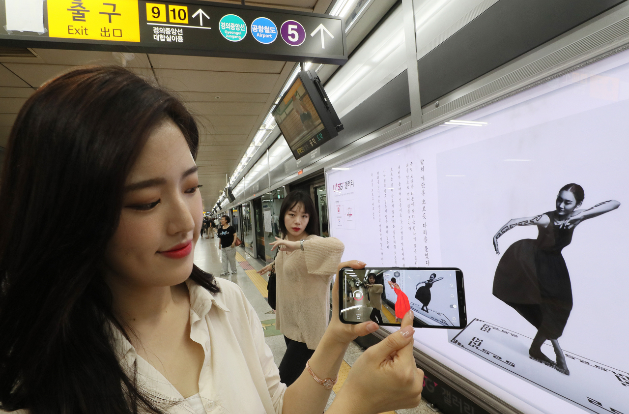 3일 오전 서울 마포구 6호선 공덕역에서 모델들이 LG유플러스의 5G 기술을 활용해 작품을 증강현실(AR)로 관람하는 'U+5G 갤러리' 를 선보이고 있다. 지하철을 기다리는 고객이 스크린도어에 설치된 미술 작품을 LG유플러스의 5G 증강현실 서비스 앱인 'U+AR'로 보면 정지된 그림에 사물이나 인물의 움직임이 가미된다. LG유플러스와 서울교통공사는 이를 위해 '지하철 6호선 공덕역 문화예술철도 구축'에 대한 업무협약을 체결했다. 연합뉴스