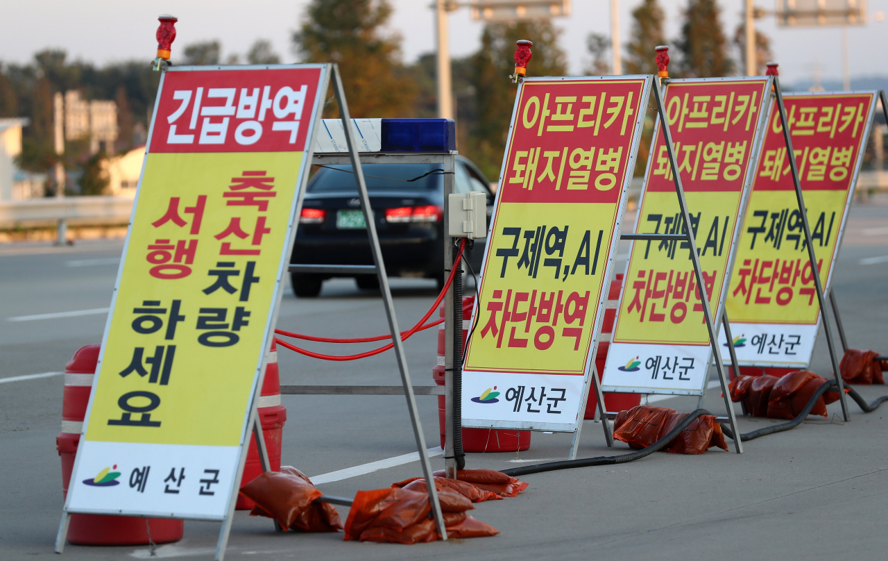 방역 당국이 지난 29일 오후 충남 예산군 한 도로에 방역 안내 표지판을 설치하고 아프리카돼지열병(ASF) 확산 방지에 총력을 기울이고 있다. 이로인해 전국 지자체가 준비중이던 축제 상당수가 취소되거나 연기됐다./연합뉴스