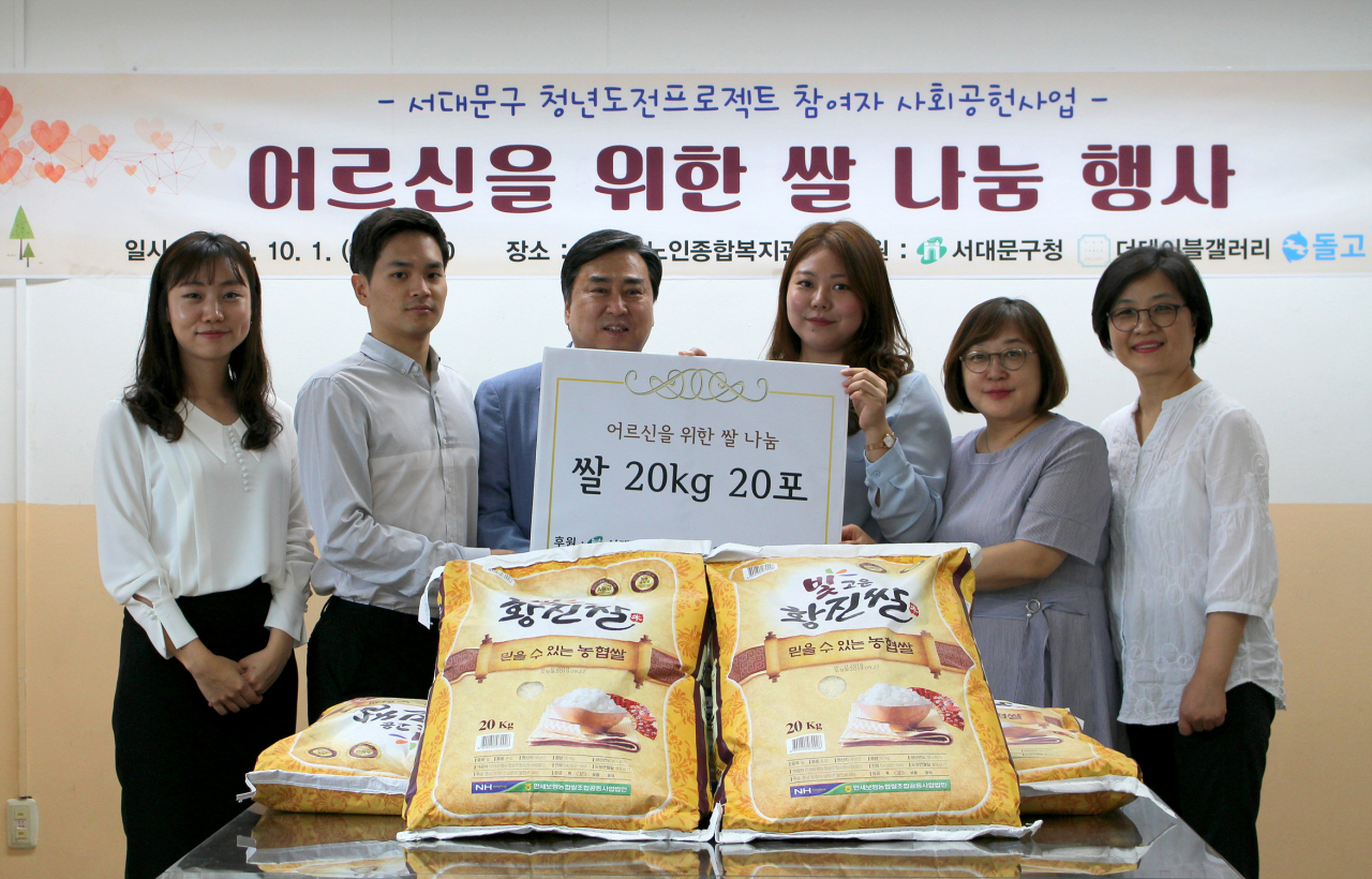 서대문구 청년도전 프로젝트에 참여하고 있는 ‘더테이블갤러리’의 공연지(오른쪽 세번째) 공동대표가 탁우상(왼쪽 세 번째) 서대문노인종합복지관장에게 취약계층 어르신들을 위한 쌀을 기부하고 있다. [서대문구 제공]