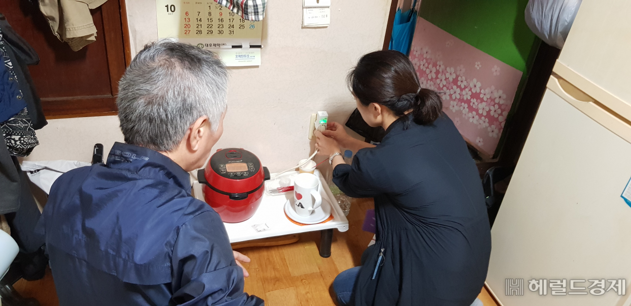 금천구청 사회복지사가 홀몸어르신 가구에 스마트플러그를 설치하고 사용법에 대해 설명하고 있다. [금천구]