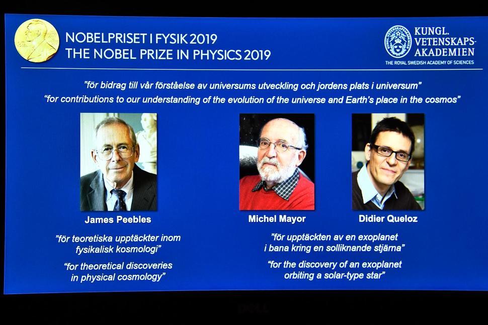 A screen displays the portraits of the laureates of the 2019 Nobel Prize in Physics, with left to right, James Peebles, Michel Mayor and Didier Queloz, during a news conference at the Royal Swedish Academy of Sciences in Stockholm, Sweden, on Tuesday. (Claudio Bresciani / TT via AP)