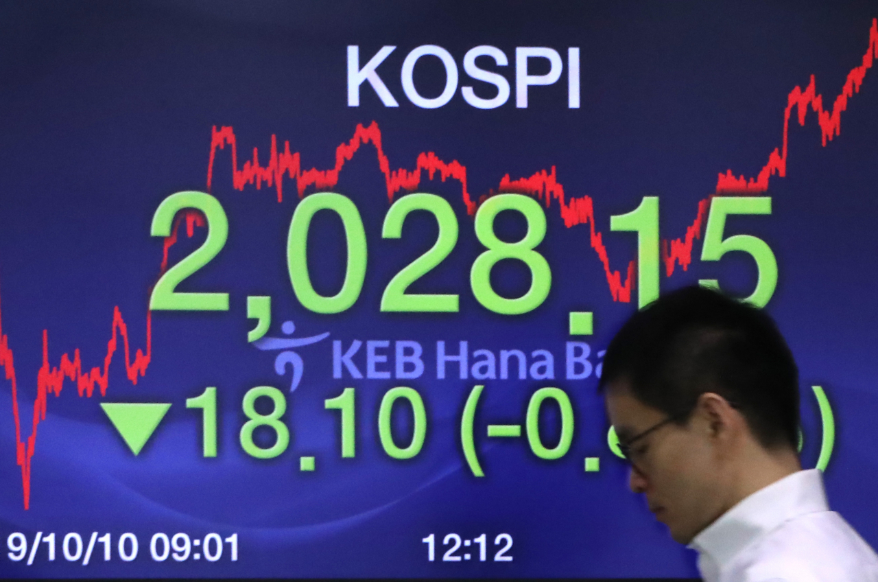 코스피가 18.10포인트 하락한 2,028.15로 장을 마감한 10일 서울 중구 KEB 하나은행 딜링룸에서 한 딜러가 전광판 앞을 지나고 있다. 연합뉴스