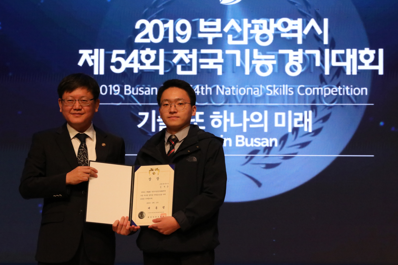 제54회 부산 전국기능경기대회 최고 영예인 대통령상을 받은 공업전자기기 직종의 김백준(부산기계공고) 선수가 상패를 받은 후 임서정 고용노동부 차관(왼쪽)과 기념사진을 찍고 있다. [고용노동부 제공]