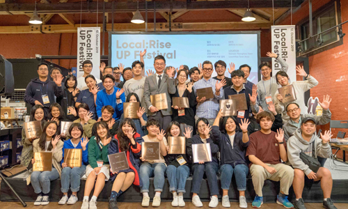 지난 12일 전북 군산 영화동에서 열린 ‘로컬라이즈 업 페스티벌’에서 23개 소셜 벤처 기업인들이 현판을 전달받고 기념촬영을 하고 있다. [SK E&S 제공]