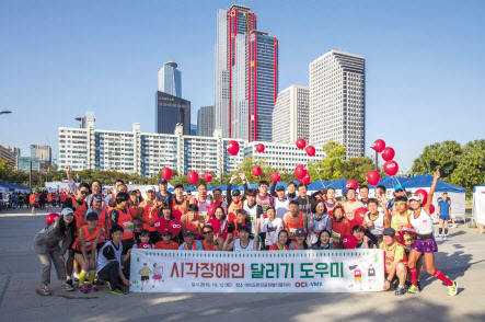 지난 12일 서울 여의도한강공원에서 열린 시각장애인 마라톤 대회에서 참가들과 OCI 임직원 봉사자들이 단체사진을 찍고 있다. [OCI 제공]