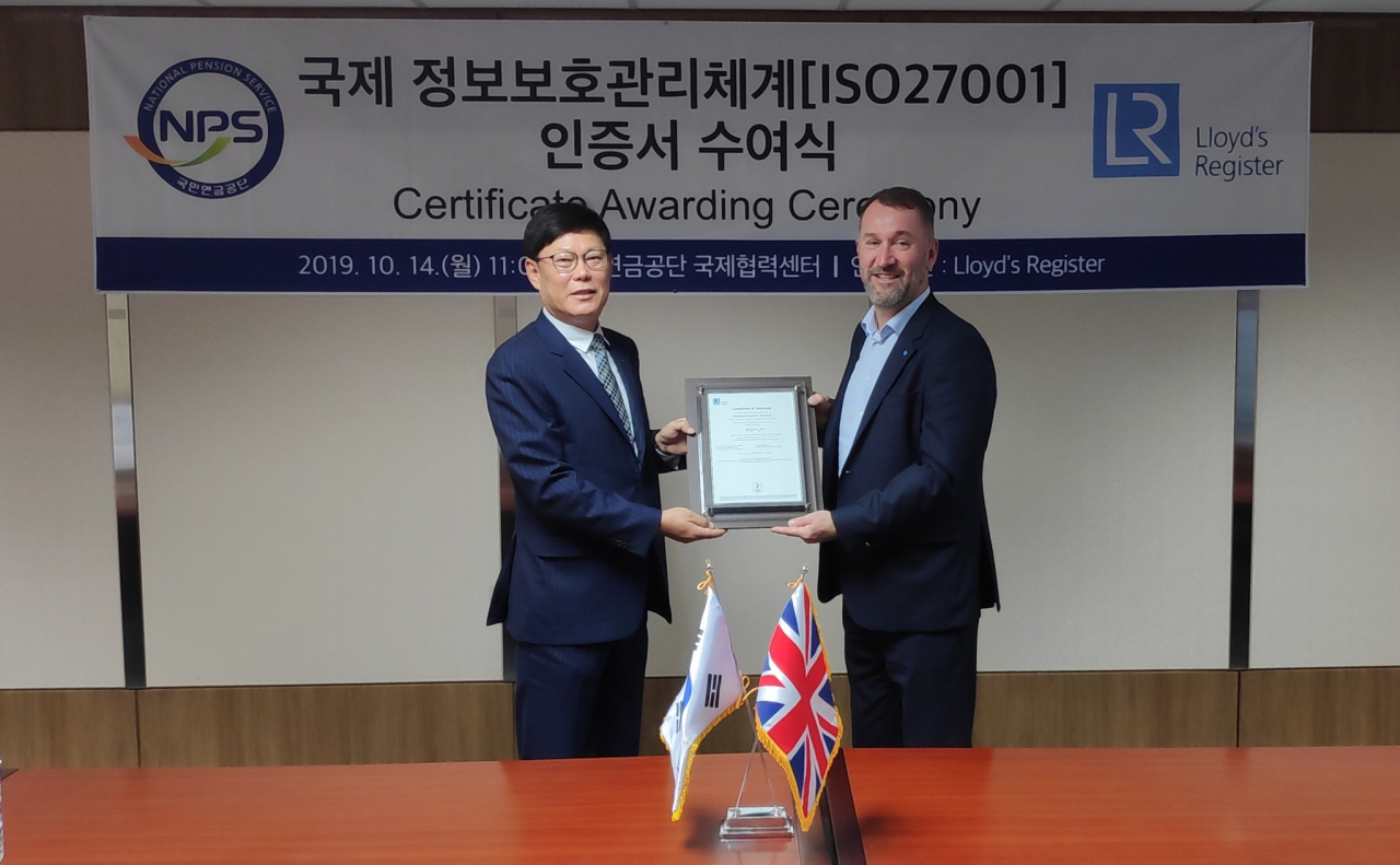 김대순 국민연금공단 정보화본부장(왼쪽)이 ISO27001 인증서를 전달받은 후 로이드 인증원의 폴 부쳐(Paul Butcher) 전무이사와 기념촬영을 하고 있다. [국민연금공단 제공]