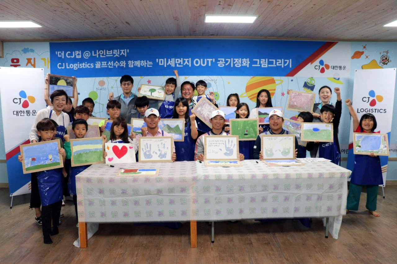 CJ대한통운 소속 골퍼 김민휘 선수(가운데), 김시우 선수(왼쪽), 이경훈 선수(오른쪽), 화가 택배기사 원성진씨(뒷편 가운데)가 아이들과 함께 기념사진 촬영을 하고 있다. [CJ대한통운 제공]