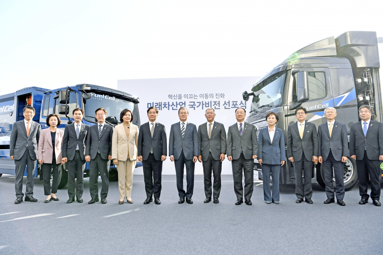(앞 줄 왼쪽 네 번째 부터) 이재명 경기도지사, 박영선 중소벤처기업부 장관, 성윤모 산업통상자원부 장관, 문재인 대통령, 정의선 현대차그룹 수석부회장, 홍남기 경제부총리 겸 기획재정부 장관, 김현미 국토교통부 장관 등이 수출형 수소전기트럭 및 수소전기청소트럭을 배경으로 기념촬영을 하고 있는 모습. [현대차 제공]