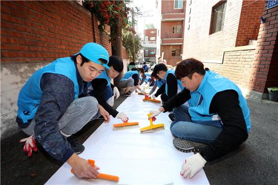 지난 15일 서울 마포구에서 대우건설 직원들이 노후주택에 도배할 벽지에 풀을 바르고 있다.[제공=대우건설]