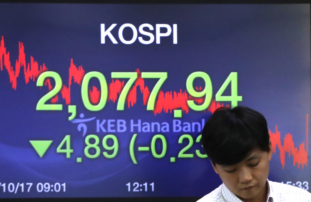 코스피가 4.89포인트 내린 2,077.94로 장을 마감한 17일 서울 중구 KEB 하나은행 딜링룸에서 한 딜러가 전광판 앞을 지나고 있다. 연합뉴스