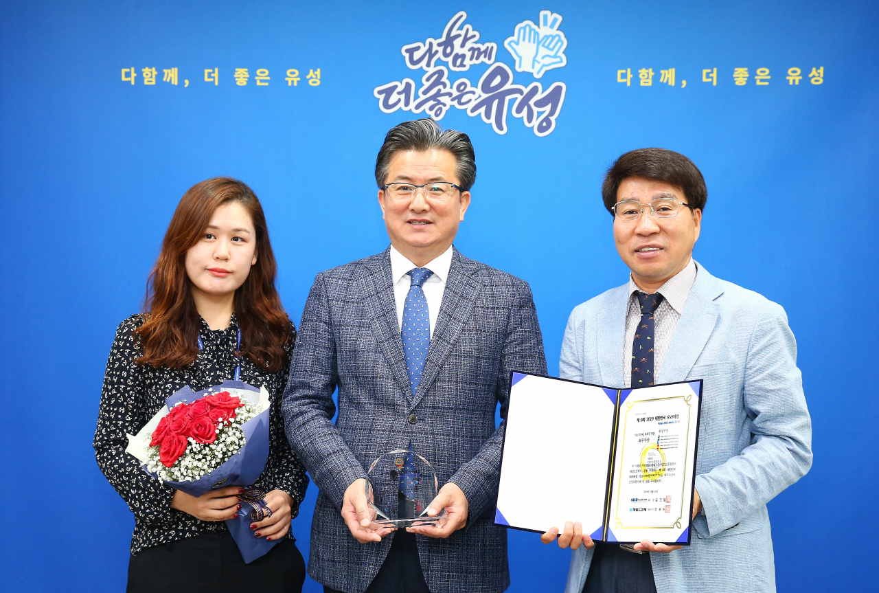 18일 구청 행복사랑방에서 정용래 유성구청장(가운데)이 송호현 홍보실장(오른쪽), 이희정 주무관(왼쪽)과 함께 표창패를 들고 기념촬영을 하고 있다.