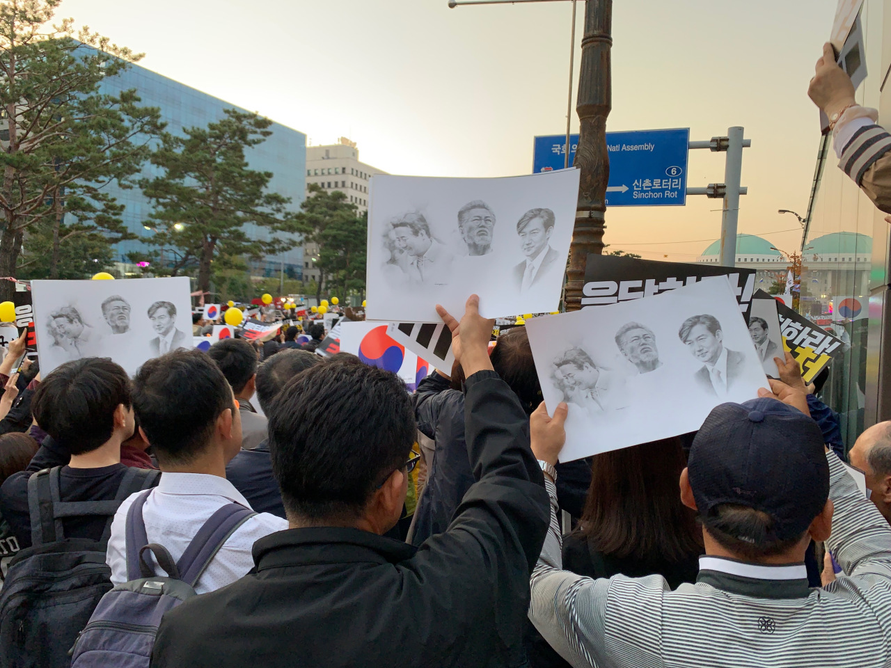 Protesters wave banners with faces of Cho, Moon and Roh. (Kim Arin/The Korea Herald)