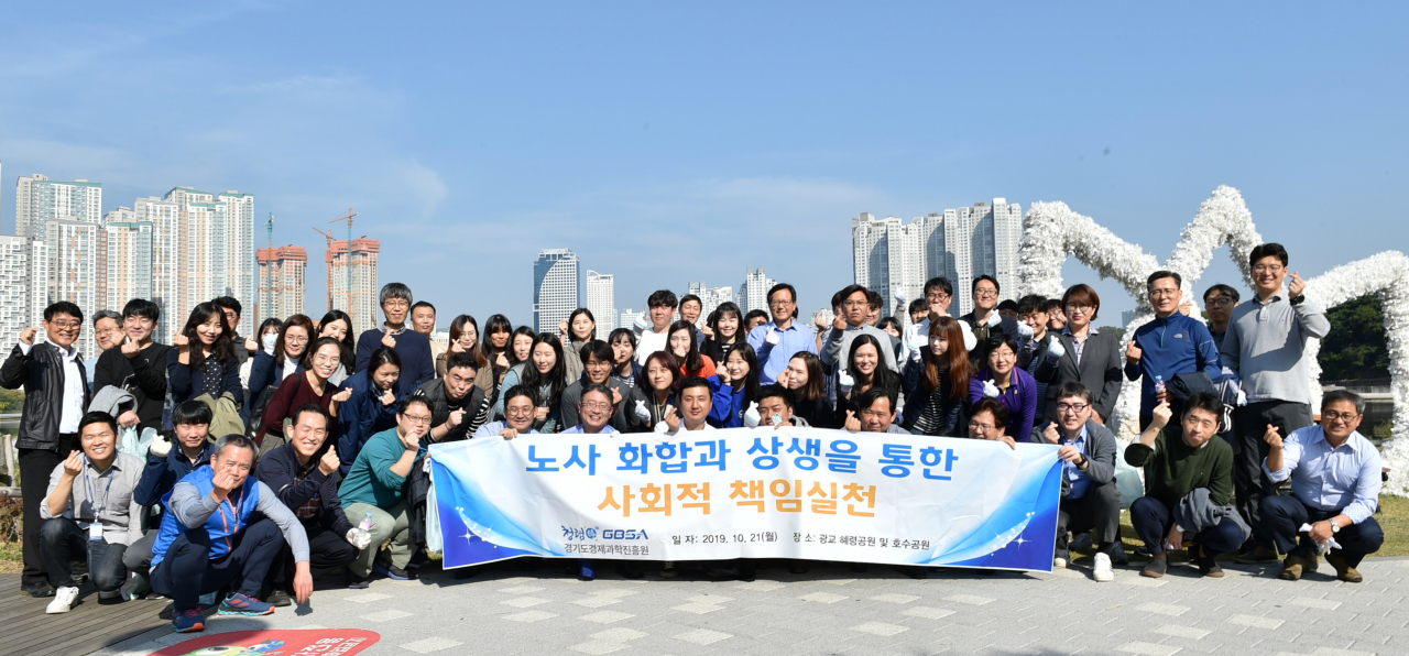 21일 열린 ‘노사화합을 위한 봉사활동’에 참여한 경과원 임직원들이 광교호수공원에서 단체사진 촬영을 하고 있다.