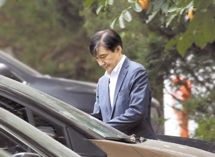 조국 전 법무부 장관이 부인 정경심 교수가 구속된 24일 오전 서울 방배동 자택에서 외출하고 있다. 정 교수의 신병을 확보한 검찰의 칼 끝은 이제 조 전 장관을 향할 전망이다. 오른쪽사진은 전날 서울중앙지법에서 영장실질심사를 마친 정 교수가 안대를 한 채 호송차로 향하는 모습. [연합]