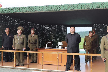 북한의 지난달 10일 초대형 방사포 시험사격 당시 김정은 위원장이 간부들과 직접 참관하고 있다. [연합]