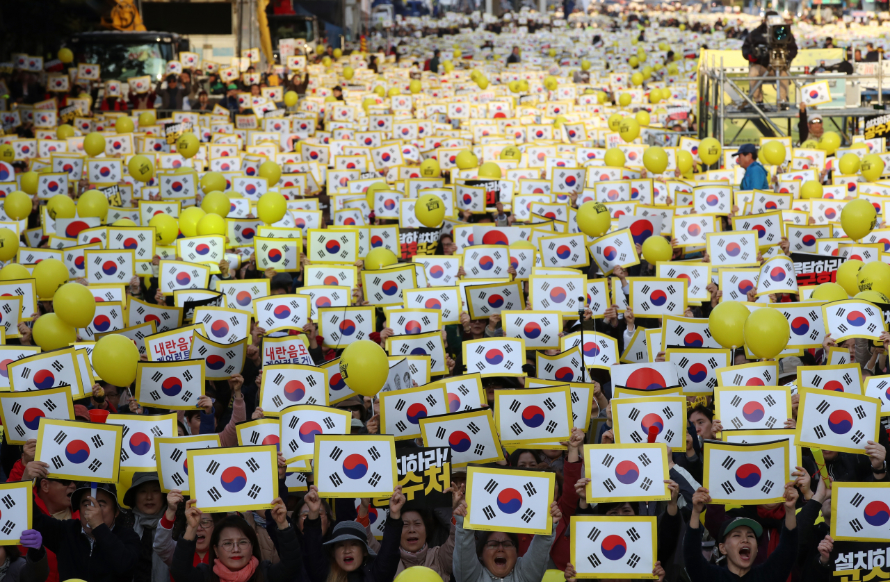26일 오후 서울 영등포구 여의도공원에서 열린 제11차 사법적폐청산을 위한 검찰개혁 촛불문화제에서 참석자들이 태극기가 그려진 손피켓을 들고 구호를 외치고 있다. [연합]