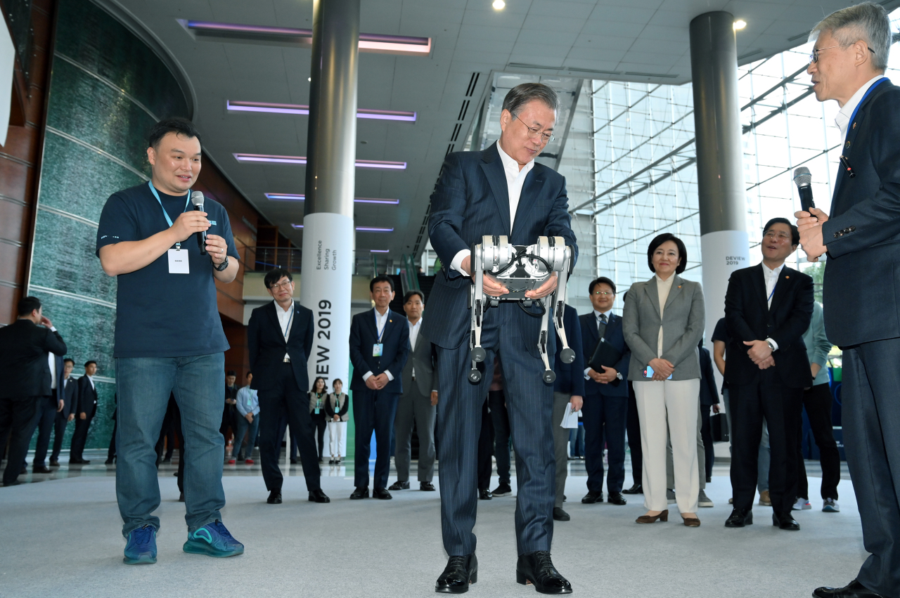 President Moon Jae-in (center) demonstrates how to use a robotic cheetah when he attends Naver’s 2019 Deview conference held at Coex conference hall in Seoul Monday. Standing left to Moon is Seok Sang-ok, who leads Naver’s research and development unit, Naver LABS. Naver