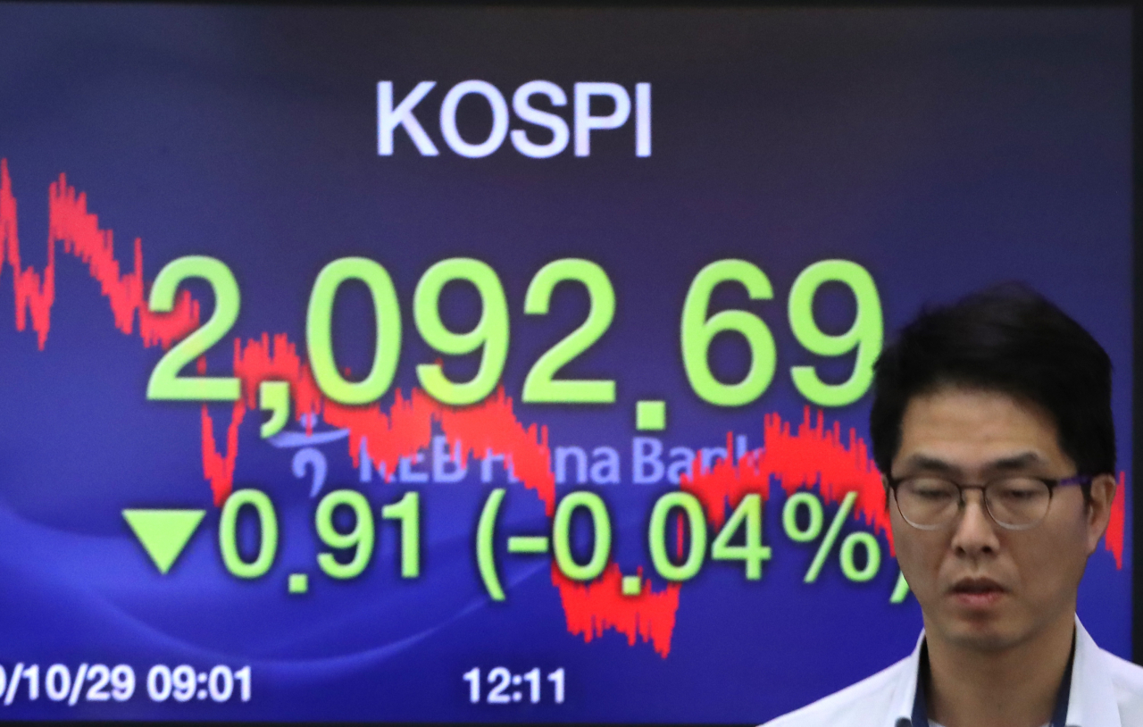 코스피가 0.91포인트 하락한 2,092.69로 장을 마감한 29일 서울 중구 KEB 하나은행 딜링룸에서 한 딜러가 전광판 앞을 지나고 있다. 연합뉴스