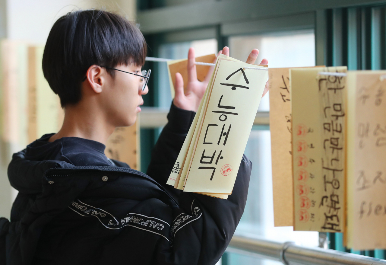 2020학년도 대학수학능력시험이 하루 앞으로 다가왔다. 컨디션 조절과 휴식으로 안정을 취하는 게 바람직하다. 사진은 지난 12일 서울 종로구 경복고 3학년 교실 복도에서 한 학생이 수능 희망 메시지를 살펴보고 있다. [연합]
