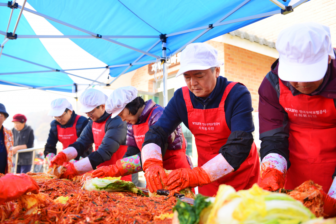 이인호(오른쪽 두번째) 한국무역보험공사 사장이 12일 ‘1사1촌’ 자매결연마을인 경기 파주 객현2리에서 진행된 ‘사랑의 김장’ 행사에서 김치를 담고 있다. ［ 한국무역보험공사 제공］