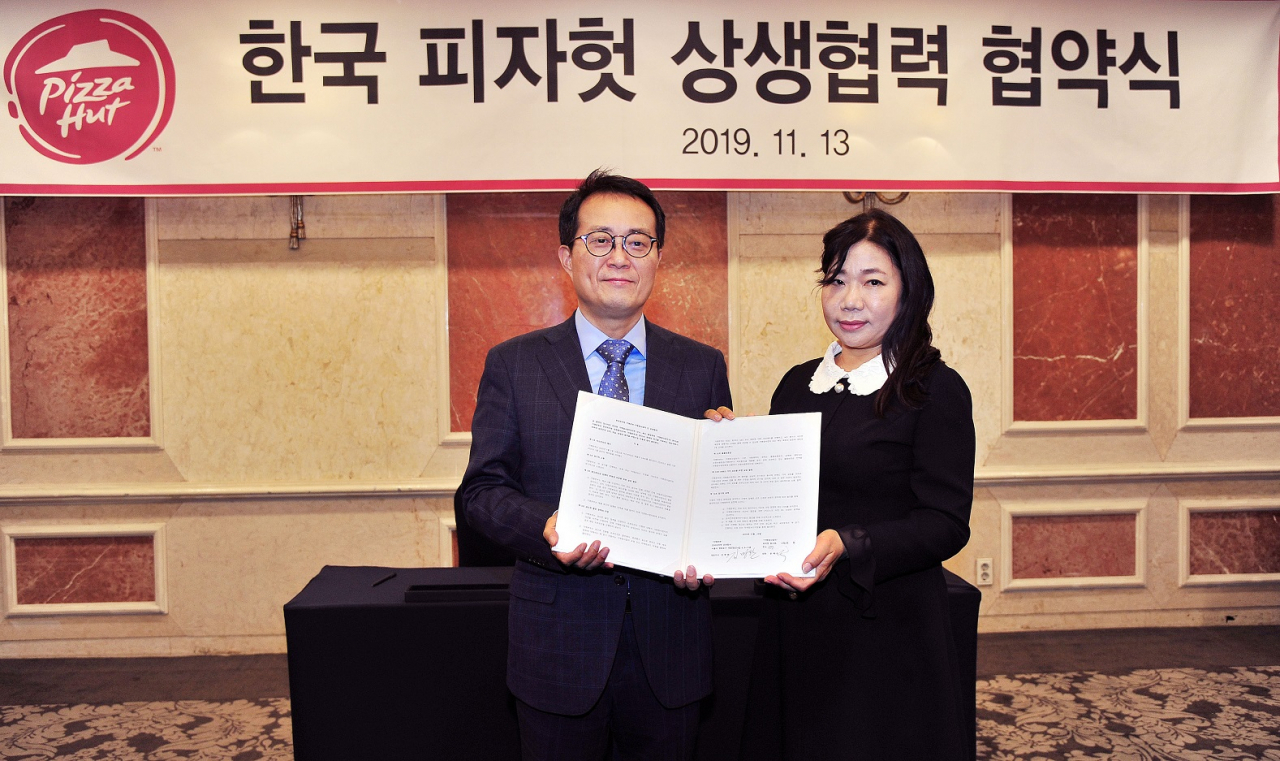 김명환 한국피자헛 대표와 윤혜순 피자헛가맹점주협의회장(피가협회장)이 상생협약 체결 후 협약서를 펼쳐보이고 있다. [제공=한국피자헛]