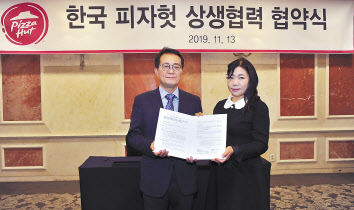 김명환 한국피자헛 대표와 윤혜순 피자헛가맹점주협의회장(피가협회장)이 상생협약 체결 후 협약서를 펼쳐보이고 있다.[한국피자헛 제공]