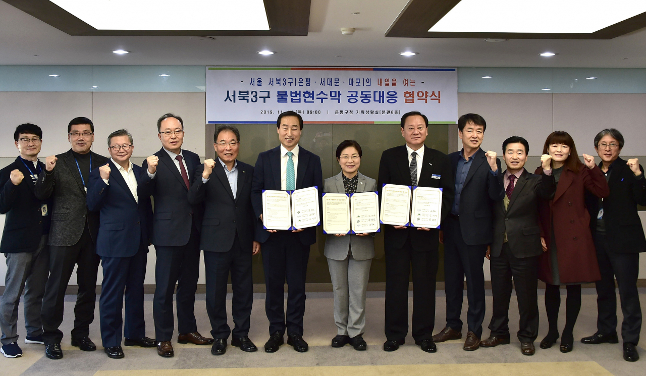 문석진(맨 왼쪽 여섯번째부터) 서대문구청장, 김미경 은평구청장, 유동균 마포구청장이 서북 3구 불법현수막 공동대응 협약을 맺은 뒤 파이팅을 외치는 각 구 관련 부서 직원들과 함께 기념촬영을 하고 있다. [서대문구 제공]