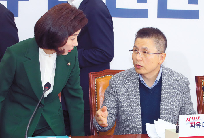황교안 자유한국당 대표(오른쪽)와 나경원 원내대표가 18일 국회에서 열린 최고위원회의에서 뭔가를 얘기하며 자리에 앉고 있다. [연합]