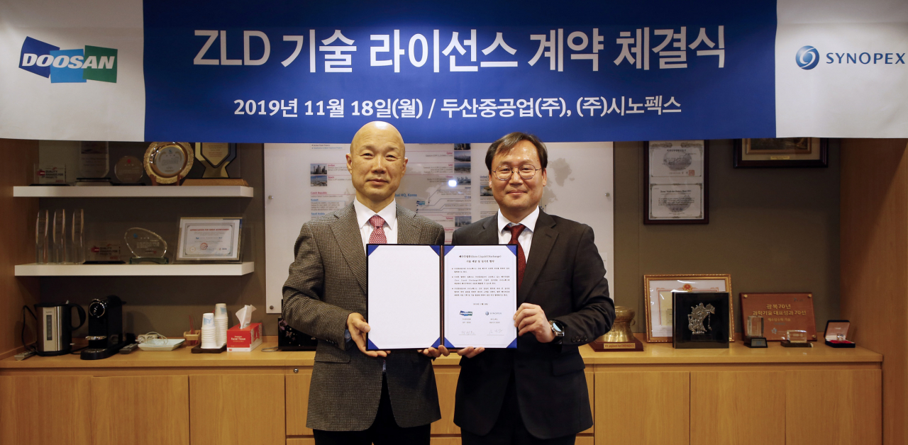 두산중공업이 18일 서울사무소에서 시노펙스와 폐수무방류처리(ZLD) 기술 라이선스 계약을 체결했다. 정성문(오른쪽) 두산중공업 플랜트 EPG BG 상무와 손경익 시노펙스 대표이사가 서명 후 기념촬영을 하고 있다. [두산중공업 제공]
