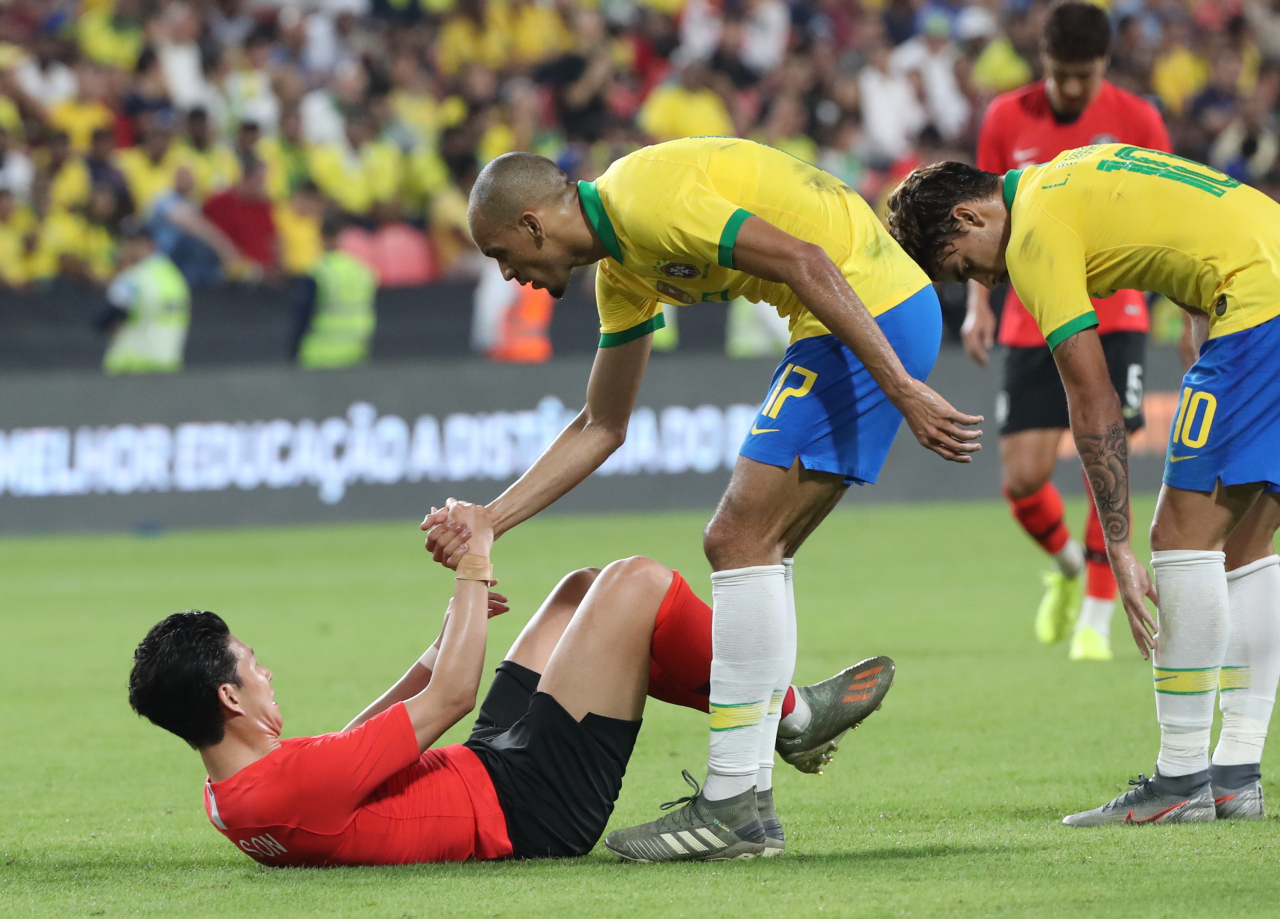 19일(한국시간) 아랍에미리트(UAE) 아부다비의 모하메드 빈 자예드 스타디움에서 열린 대한민국과 브라질 대표팀의 친선경기에서 파비뉴(리버풀)가 파울을 당한 손흥민을 일으켜 세우고 있다. [연합]