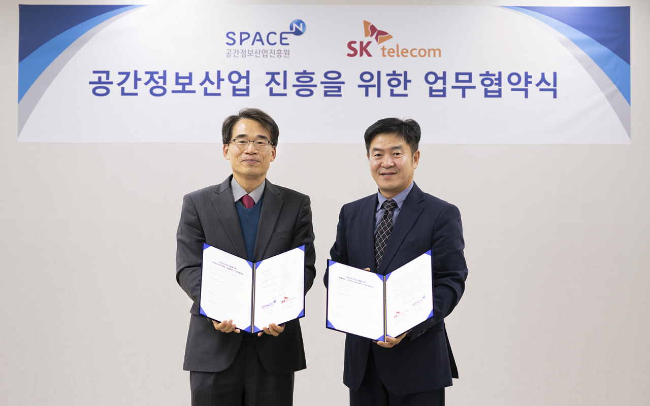 정창권 인프라 엔지니어링 그룹장(오른쪽)이 김수곤 공간정보산업진흥원장과 21일 '3D 기반 공간정보 데이터 활용을 위한 업무 협약'을 맺고 기념촬영을 하고 있다. [SK텔레콤 제공]