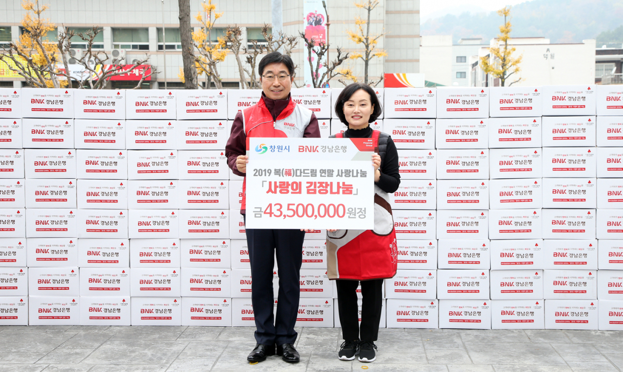 BNK경남은행 황윤철 은행장(사진 왼쪽)이 창원시 허성무 시장 부인 이미숙 여사에게 ‘사랑의 김장 김치 기탁 증서’를 전달하고 있다.