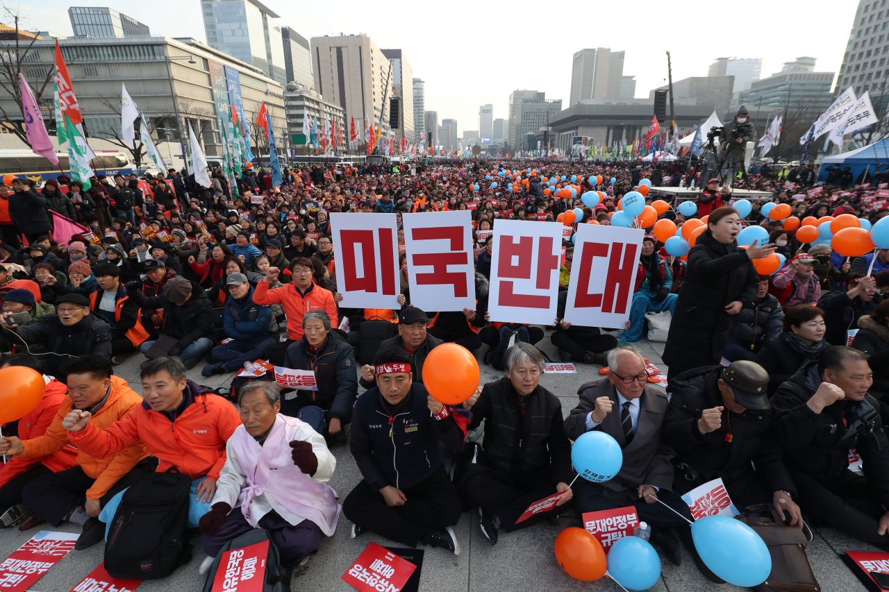 30일 오후 서울 광화문광장에서 열린 2019 전국민중대회에서 참가자들이 미국반대를 외치는 내용이 담긴 피켓을 들고 있다. [연합]