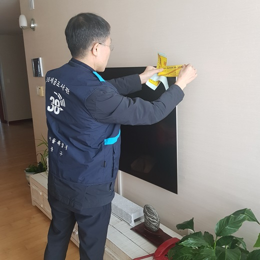 중구 38세즘조사관이 상습 고액 체납자의 집을 찾아 동산에 압류 딱지를 붙이고 있다. [중구 제공]