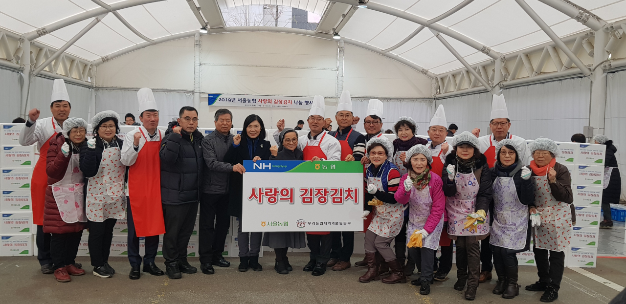 서울농협 임직원 및 고향주부모임 회원들이 사랑의 김장김치 나눔행사에서 직접 담근 400kg의 김치 포장박스를 배경으로 기념촬영을 하고 있다. [농협 제공]
