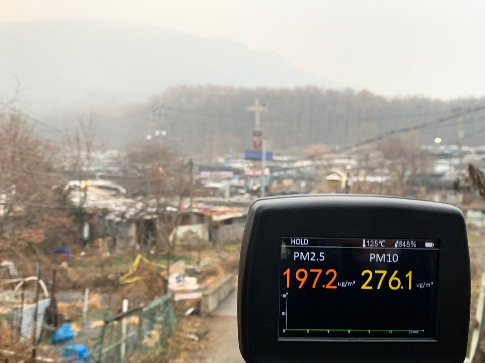 11일 오전 서울 강남구 구룡마을 입구에서 측정한 미세먼지 모습. 마을 뒤 대모산이 미세먼지로 인해 흐릿하게 보인다. [사진=박상현 기자]