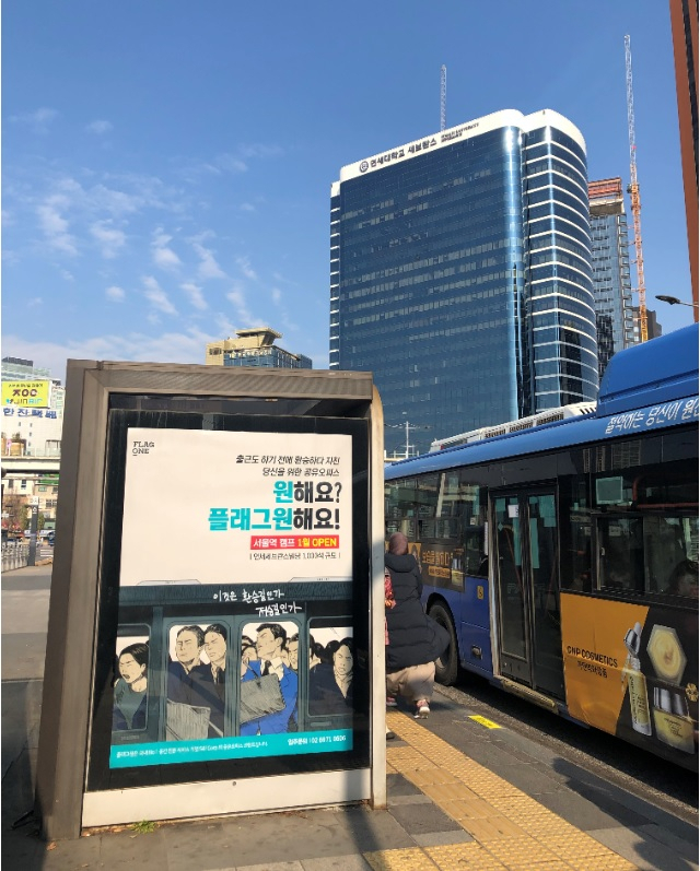 플래그원을 소개하는 광고판 뒤로 플래그원 서울역캠프가 들어설 연세세브란스 빌딩의 모습이 보인다.