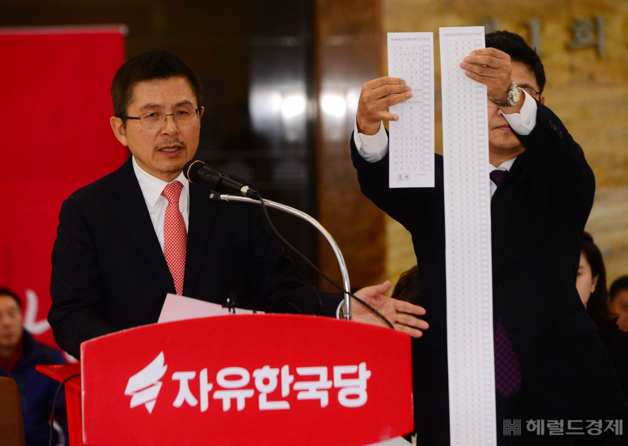 23일 국회 로텐더홀에서 열린 자유한국당 최고위원회의에서 황교안 대표가 연동형 비례제를 비판하는 발언을 하는 동안 성동규 여의도 연구소장이 길어진 가상의 투표용지를 보여주고 있다. [박해묵 기자/mook@heraldcorp.com]