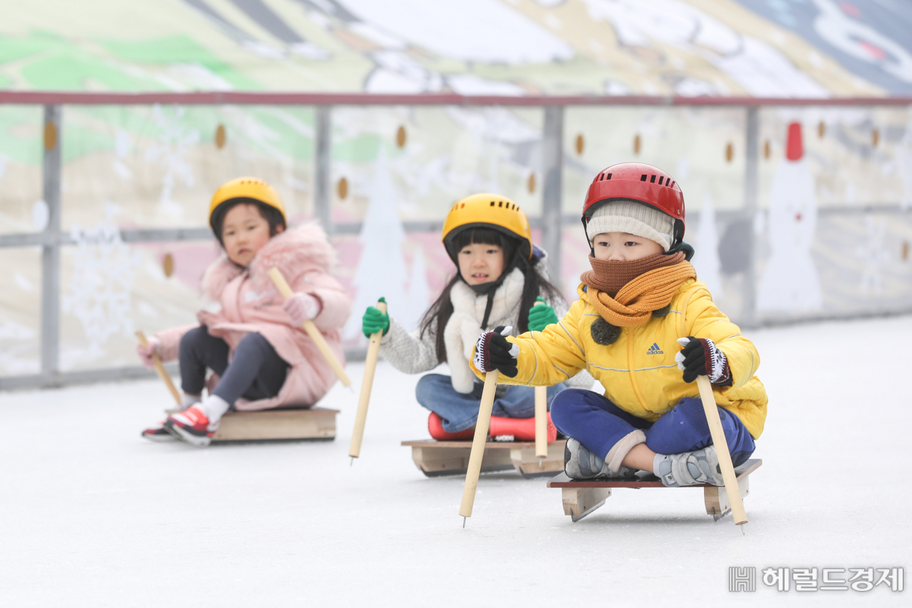 27일 오전 서울 서초구 서리풀 얼음썰매장에서 어린이들이 강추위에도 아랑곳 하지 않고 목도리에 안전모자를 쓴 채로 썰매를 타고 있다. 서초구가 조성한 이 썰매장은 내년 2월 9일까지 운영한다. [서초구]