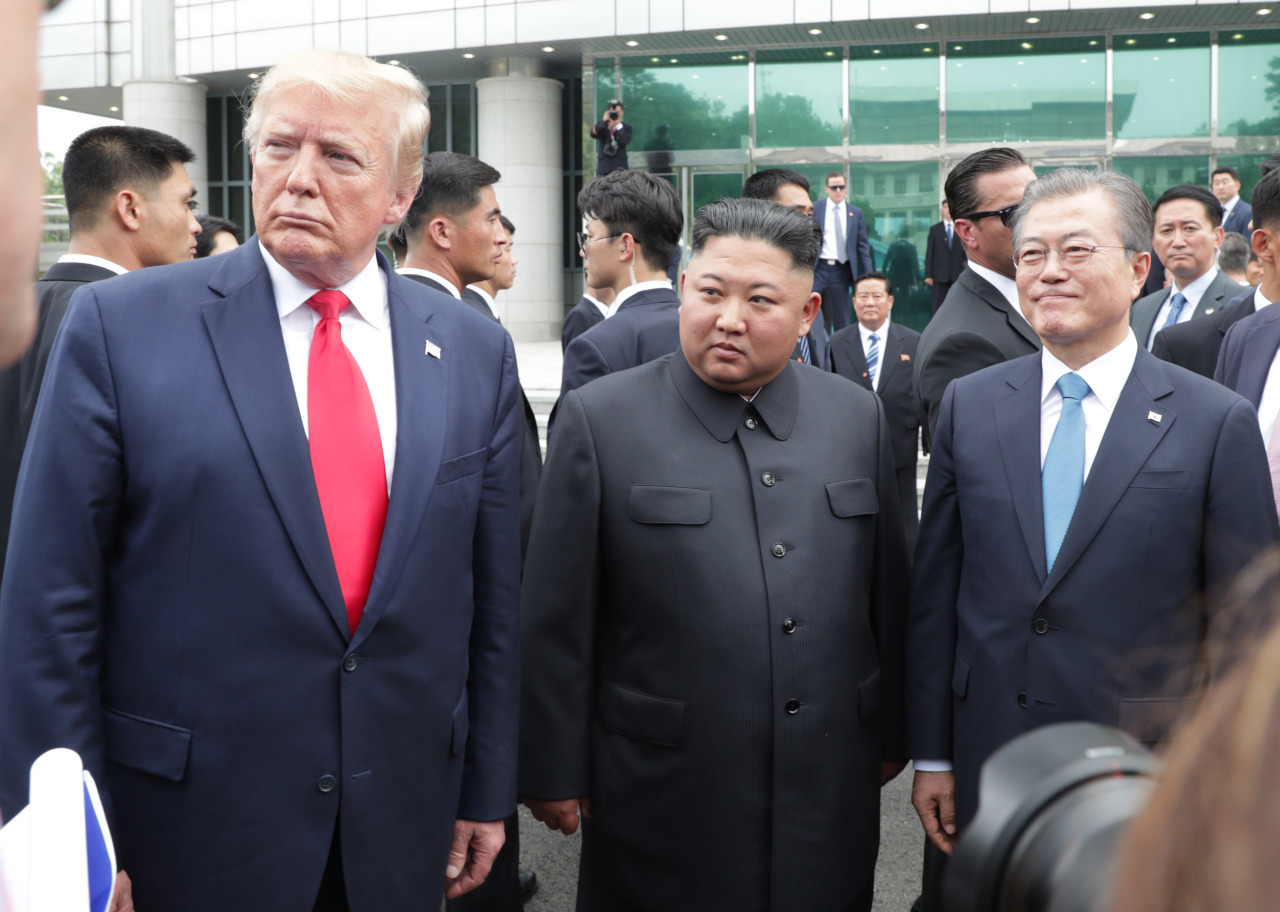US President Donald Trump (left), North Korean leader Kim Jong-un and South Korean President Moon Jae-in stand next to each other in the southern part of the Joint Security Area in the DMZ on June 30. (Yonhap)