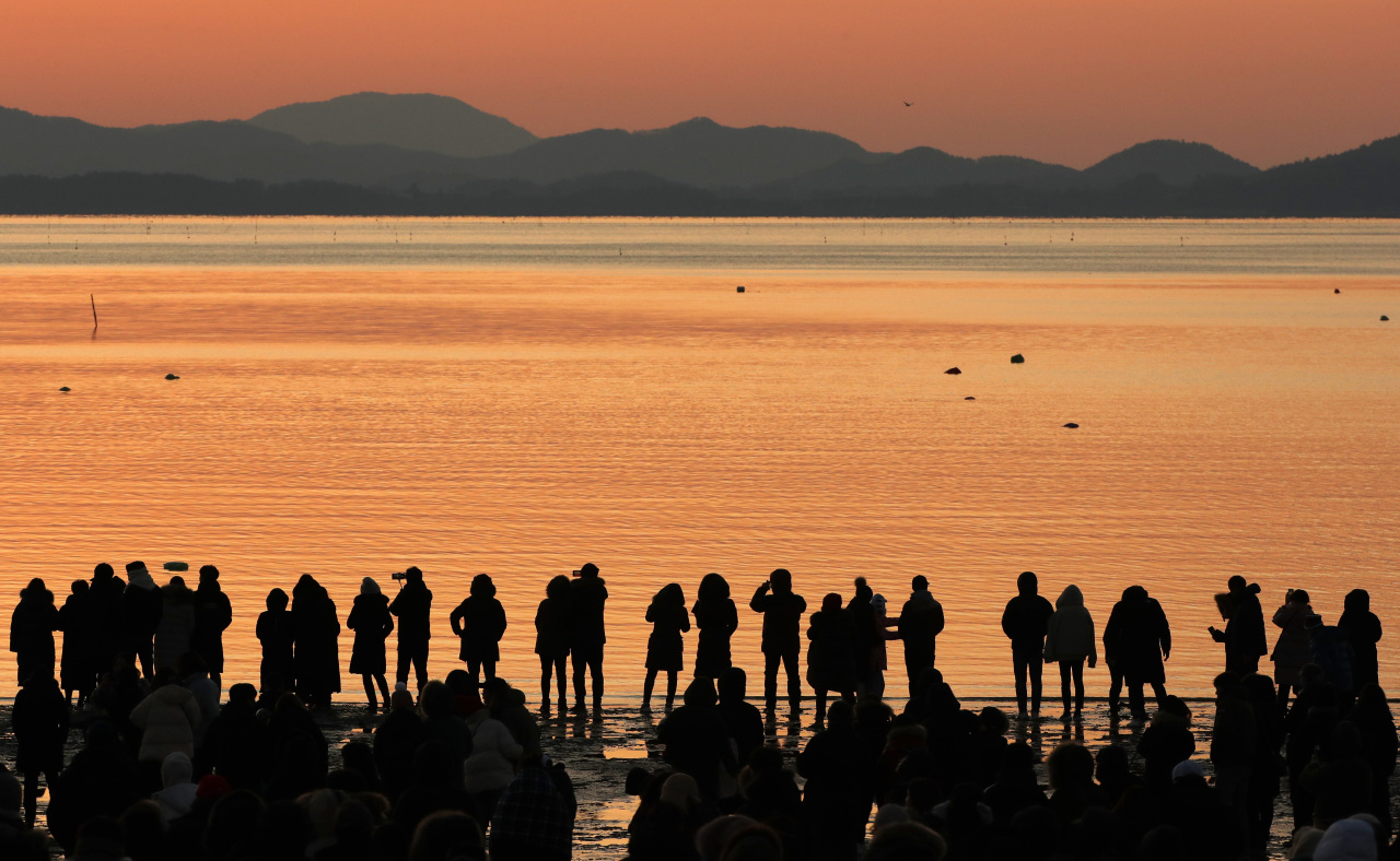 A crowd watches the sunrise from a beach in Gangneung, Gangwon Province, Wednesday. (Yonhap)