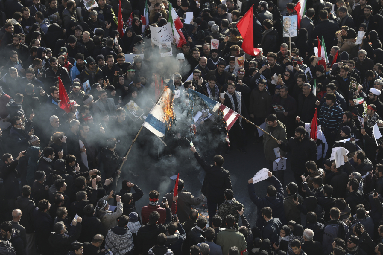 Mourners burn mock flags of the US and Israel during a funeral ceremony for Iranian Gen. Qassem Soleimani and his comrades, who were killed in Iraq in a US drone strike on Friday, at the Enqelab-e-Eslami (Islamic Revolution) square in Tehran, Iran, Monday. (AP-Yonhap)