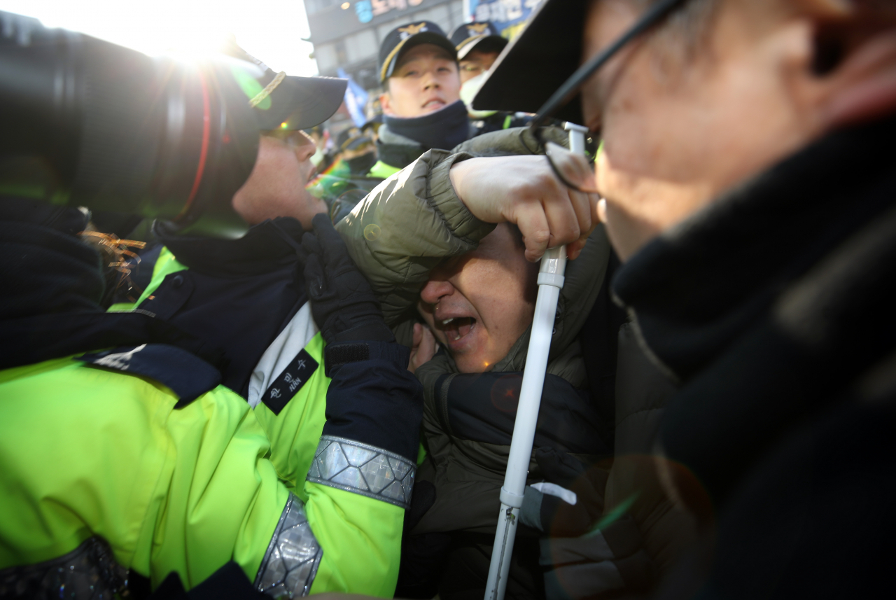 지난 4일 오후 서울 종로구 경복궁역 인근에서 보수 진영 단체 등이 청와대 부근으로 행진하자, 청와대 인근 서울맹학교 학부모, 학생 등이 “맹학교 학생들의 학습권·이동권을 침해하는 과도한 시위를 규탄한다”며 집회를 하다 경찰의 제지를 받고 있다. [연합]