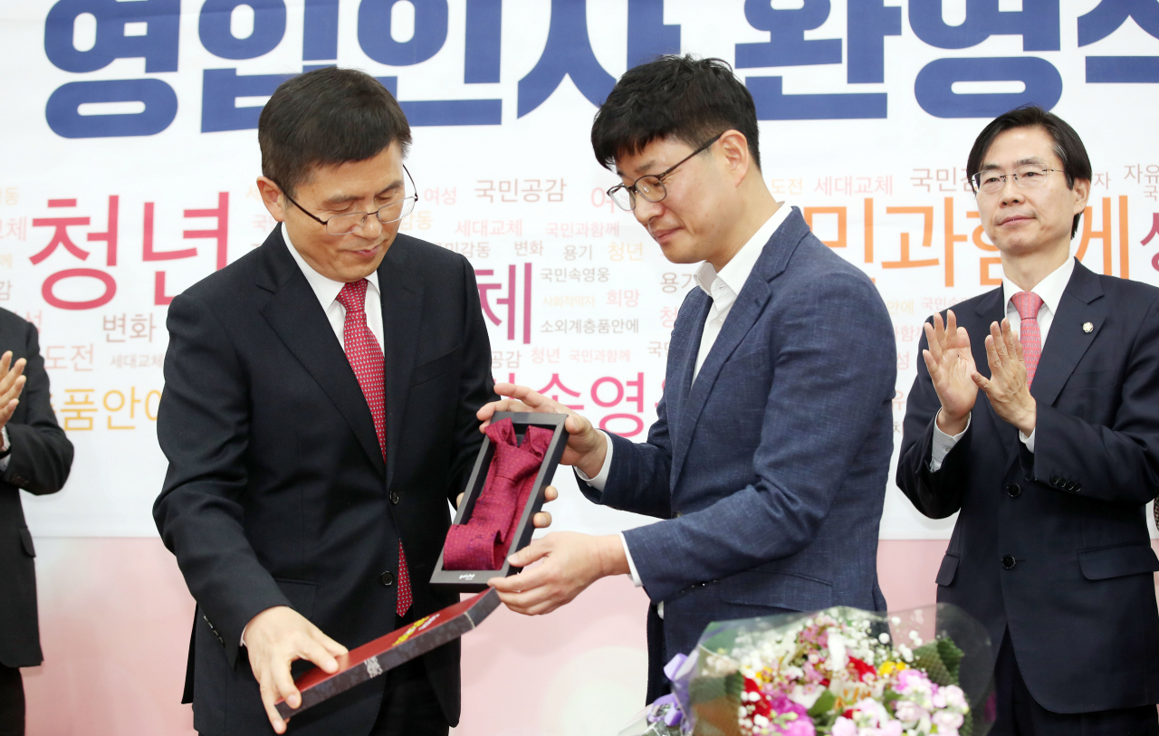 제21대 총선을 앞두고 자유한국당에 영입된 산업재해 공익신고자 이종헌 씨가 16일 오전 국회에서 열린 한국당 영입인사 환영식에서 황교안 대표로부터 붉은 넥타이를 전달받고 있다.[연합]