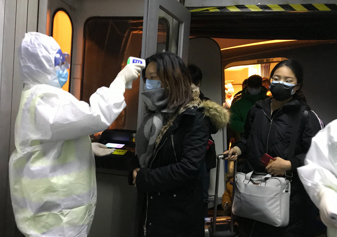 22일 중국 베이징 공항에서 방호복을 입은 검역관이 신종 코로나바이러스가 시작된 우한에서 출발해 들어오는 승객들의 체온을 측정하고 있다. [연합]