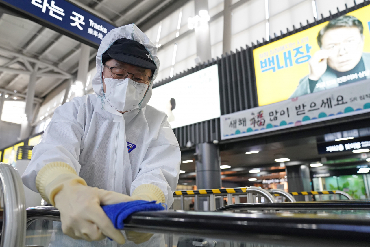 지난 23일 오전 서울 강남구 SRT 수서역에서 관계자가 에스컬레이터 손잡이를 소독하고 있다. [사진=연합]