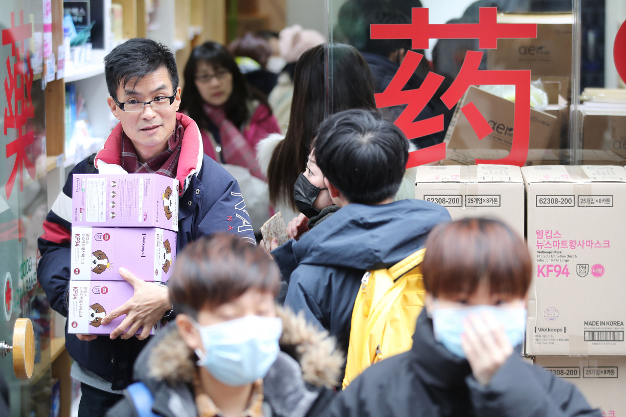 27일 오후 중구 명동의 한 약국에서 외국인 관광객이 마스크를 박스채로 구입한 뒤 나서고 있다. [연합뉴스]