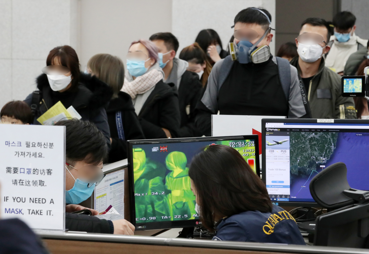 지난 28일 부산 강서구 김해국제공항 입국장에서 중국발 승객들이 검역대를 통과하고 있다. [연합]