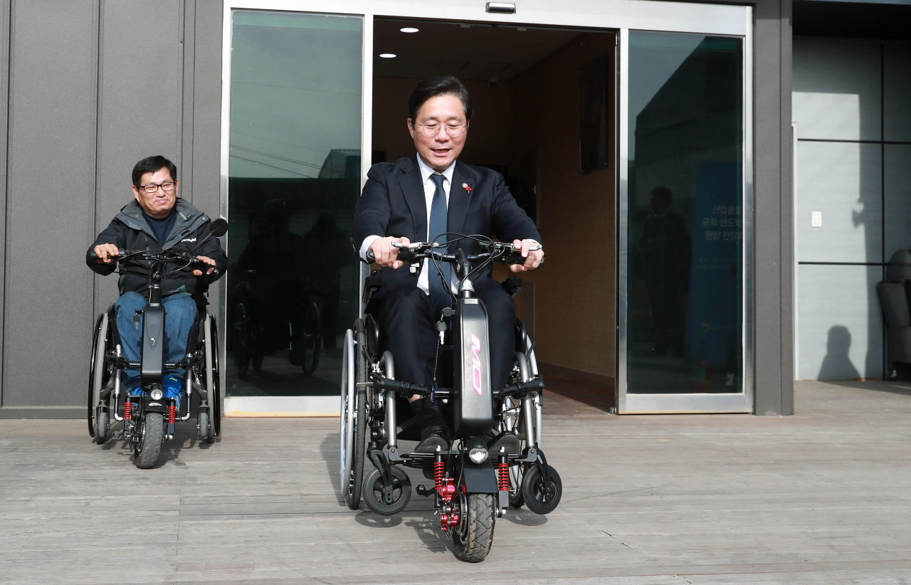 성윤모 산업통상자원부 장관이 29일 경기 김포 ㈜알에스케어서비스를 방문, 수동휠체어인 전동보조키트를 탑승하고 있다. ㈜알에스케어서비스가 개발한 전동보조키트는 수동휠체어의 앞부분에 장착해 장애인의 이동 편의성 등을 높이기 위한 기구로 수입 전동보조키트 대비 약 60% 저렴하다.［산업통상자원부 제공］
